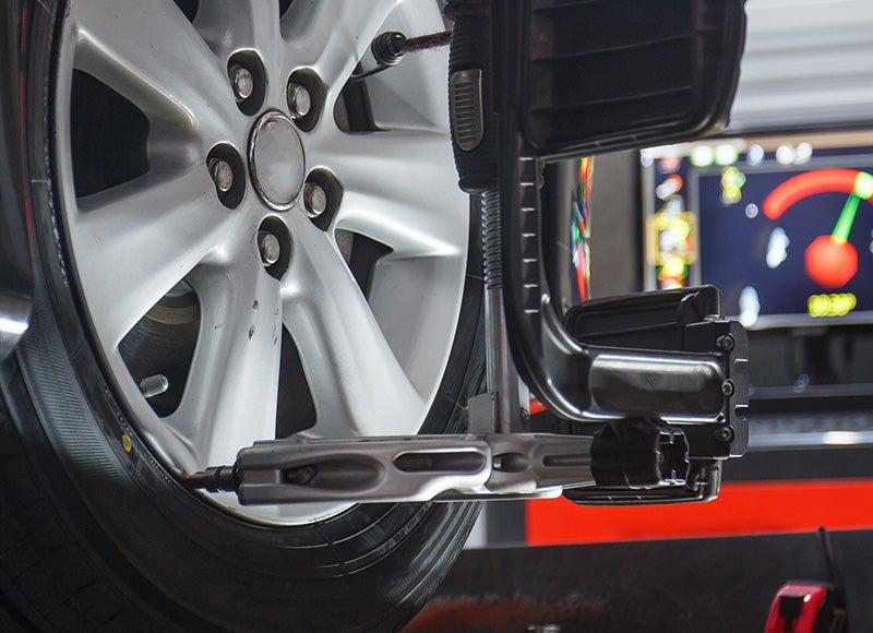 Vehicle wheel mounted on a wheel alignment machine with alignment sensors attached, used for precision tire and suspension adjustment